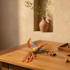 A colorful crocheted bird keychain with orange, blue, and green details lies on a wooden table next to a small tray of wooden beads. In the background, a terracotta vase with green stems sits in a recessed wall niche under warm sunlight.