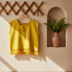Yellow sleeveless top with fringe details on a beige background