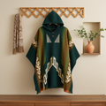 Green and brown patterned poncho on a wooden surface with a decorative wall in the background