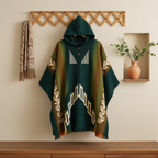 Green and brown patterned poncho on a wooden surface with a decorative wall in the background