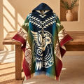 A hooded woven poncho blanket with a South American-inspired geometric and bird motif, draped over a rustic wooden bench in a warm, sunlit room.
