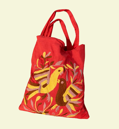 Red tote bag with colorful bird design on a beige background