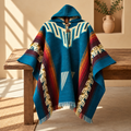 A hooded woven poncho with a Southwestern geometric pattern, draped over a rustic wooden bench in a warm, sunlit room.