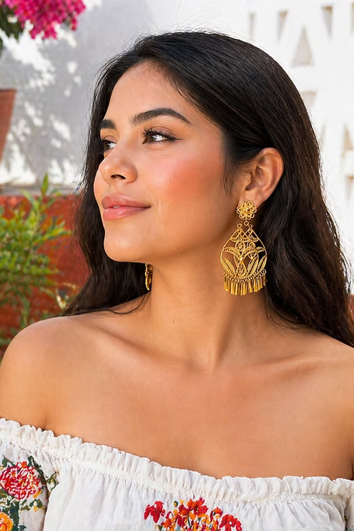 Woman wearing gold earrings with a blurred outdoor background